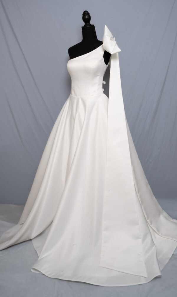 satin wedding dress with statement bow and chapel train displayed on mannequin, side view, Laurel&Lace bridals boutique